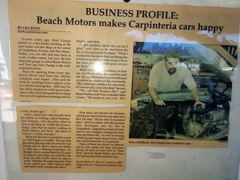 The Coastal View newspaper profile of Beach Motor & Tires, framed on the wall, with a photo of Abel Zuniga under a hood