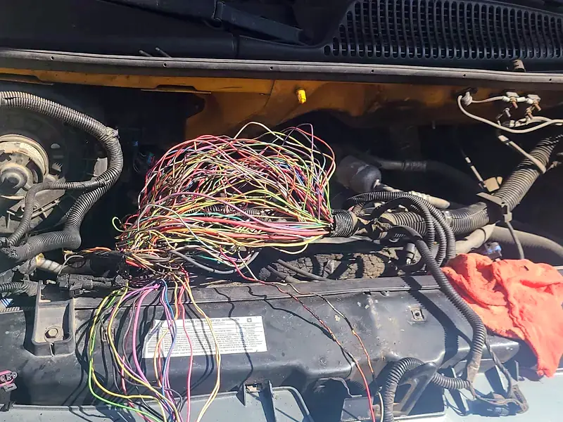 An engine harness laid open on a Chevy van during an electrical repair
